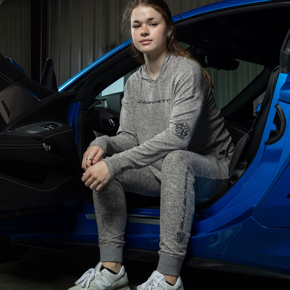 Woman sitting in a blue Corvette wearing the Corvette Ladies Charcoal Loungewear Hoodie 