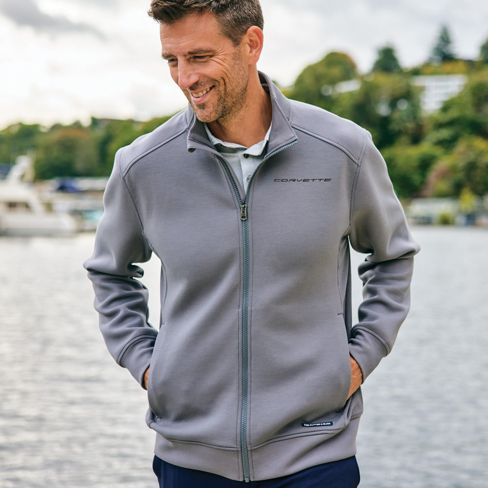 Man wearing a gray jacket with Corvette script standing by a waterfront