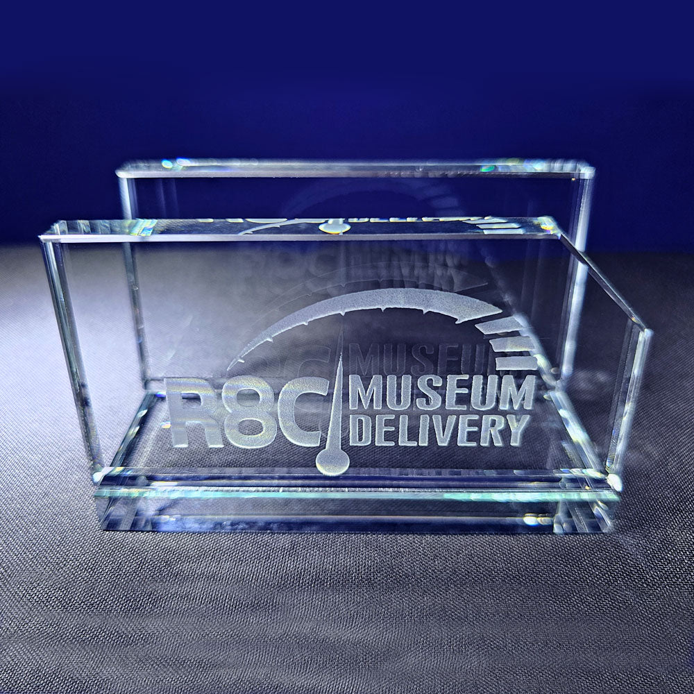 The R8C Museum Delivery Glass Business Card Holder shown sitting on a desk.